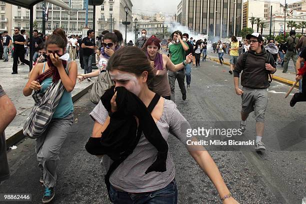 Protesters flee from tear gas deployed by Greek riot police as they clash on May 5, 2010 in Athens, Greece. Three people have died after protesters...