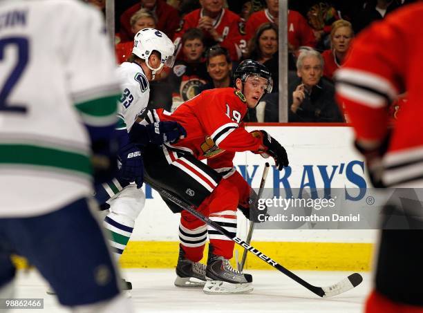 Jonathan Toews of the Chicago Blackhawks looks to pass in traffic under pressure from Henrik Sedin of the Vancouver Canucks in Game Two of the...