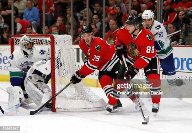 Patrick Kane of the Chicago Blackhawks looks to pass the puck past teammate Jonathan Toews as Shane O'Brien of the Vancouver Canucks closes in and...