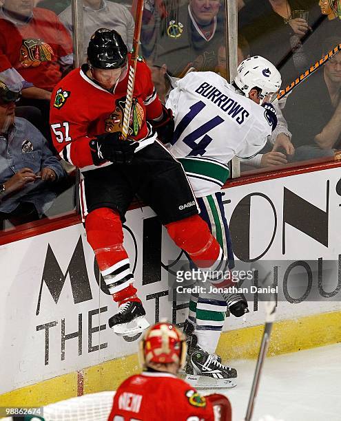 Alexandre Burrows of the Vancouver Canucks checks Brian Campbell of the Chicago Blackhawks into the boards behind the net as Antti Niemi watches in...
