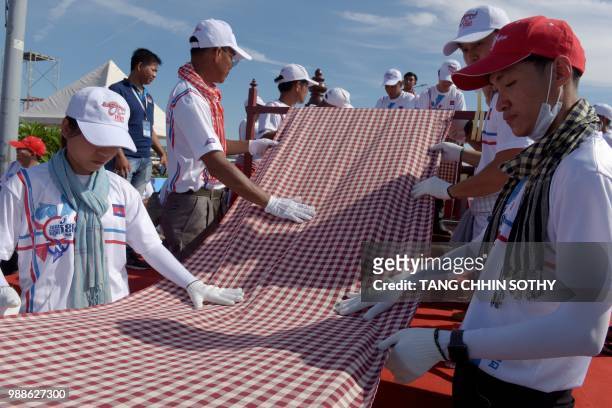 Cambodians roll out a 1,149.8 metre-long krama scarf so it can be declared as the world's longest hand woven scarf, in Phnom Penh on July 1, 2018. -...