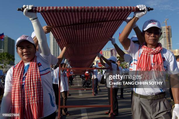 Cambodians hold up a 1,149.8 metre-long krama scarf during a ceremony to declare it as the world's longest hand woven scarf, in Phnom Penh on July 1,...