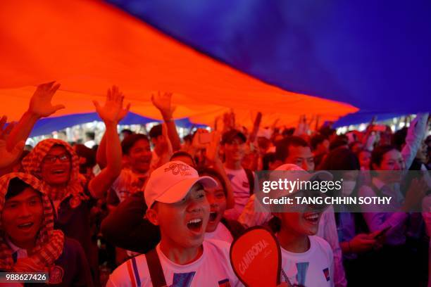 Cambodians cheer under a large national flag as a 1,149.8 metre-long krama scarf is declared as the world's longest hand woven scarf, in Phnom Penh...