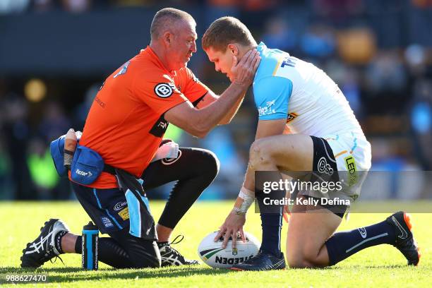 Dale Copley of the Titans is attended to by medical staff during the round 16 NRL match between the Wests Tigers and the Gold Coast Titans at...