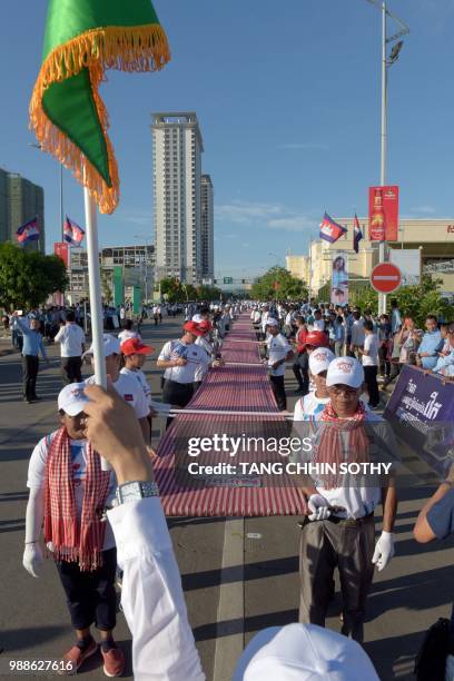 Cambodians hold a 1,149.8 metre-long krama scarf during a ceremony to declare it as the world's longest hand woven scarf, in Phnom Penh on July 1,...