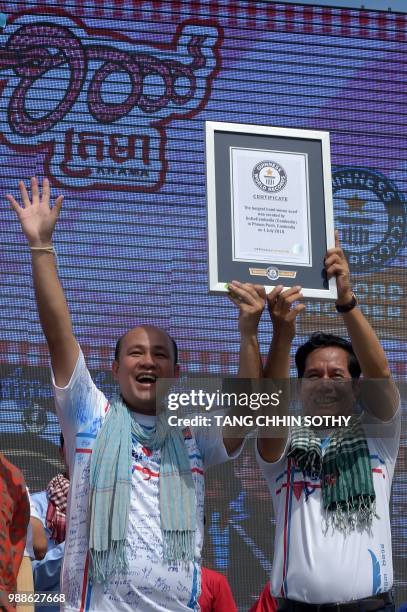 Hun Many , son of Cambodian Prime Minister Hun Sen, and Phnom Penh Governor Khuong Sreng raise a Guinness World Records certificate after a krama...