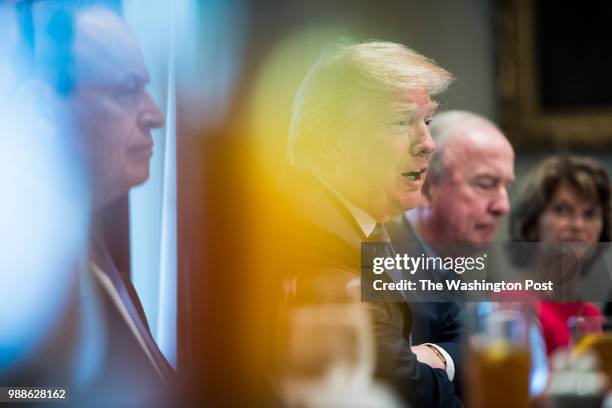 President Donald J. Trump, flanked by Sen. Richard Shelby, R-Ala. And Rep. Rodney Frelinghuysen, R-N.J., is seen through drinking glasses as he...