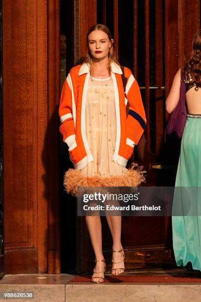 Kate Bosworth walks the runway and wears an orange coat, a beige dress with fur, golden heels, during the Miu Miu Cruise Collection show, outside the...