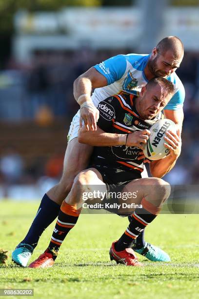 Chris Lawrence of the Tigers is tackled by Tigers defense during the round 16 NRL match between the Wests Tigers and the Gold Coast Titans at...