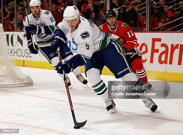 Christian Ehrhoff of the Vancouver Canucks controls the puck in front of teammate Shane O'Brien and John Madden of the Chicago Blackhawks in Game Two...