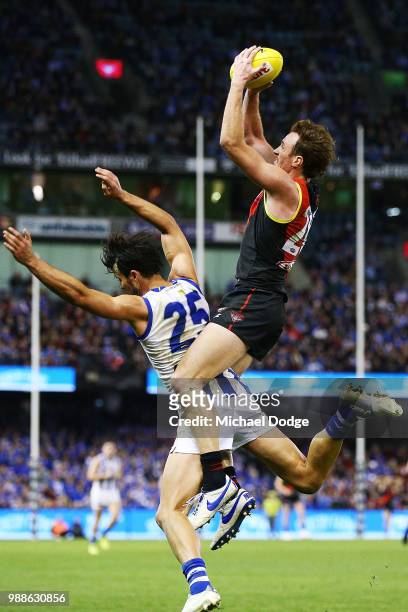 Mitch Brown of Essendon marks the ball against Robbie Tarrant of the Kangaroos during the round 15 AFL match between the Essendon Bombers and the...