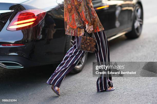 Guest wears a brown checked rectangular bag, flared striped dark blue pants, an orange floral printed jacket, outside the Miu Miu Cruise Collection...