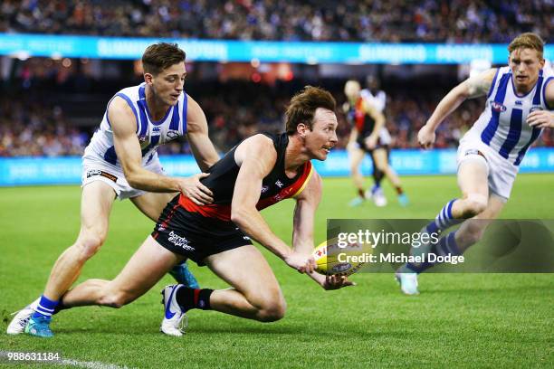 Mitch Brown of Essendon handballs from Shaun Atley of the Kangaroos during the round 15 AFL match between the Essendon Bombers and the North...