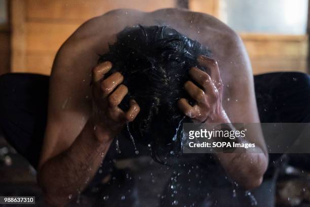 An Afghan refugee washes himself using warm water and soap as steam evaporates off his body during a cold winter in the Barracks. The Barracks in...