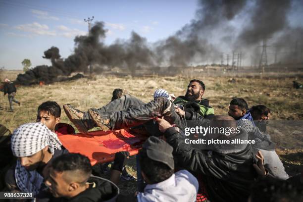 Dpatop - Palestinian protesters carry a wounded man during clashes with Israeli forces near the border fence with Israel in Nahal Oz, east of Gaza...