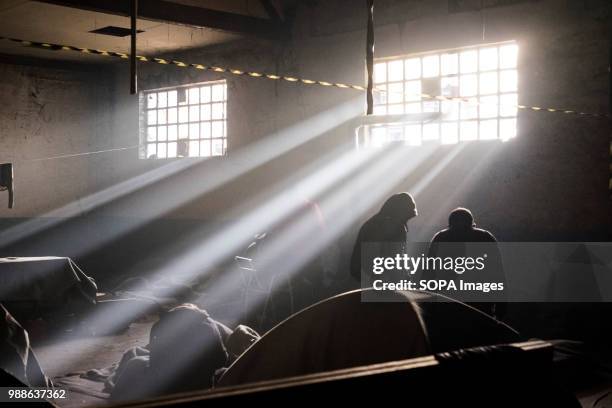 Two men talk between themselves as light shines through the windows in the Barracks. The Barracks in Belgrade were abandoned buildings behind the...