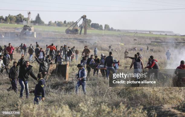 Dpatop - Palestinian protesters carry a wounded man during clashes with Israeli forces near the border fence with Israel in Nahal Oz, east of Gaza...