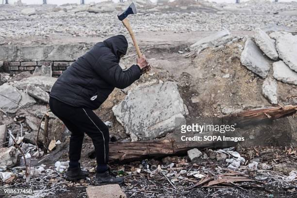 Migrant from Pakistan cuts wood from an old railway sleeper outside the Barracks. The Barracks in Belgrade were abandoned buildings behind the...
