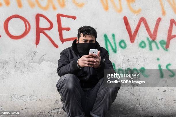 An Afghan refugee uses his phone to contact friends and family back home. The Barracks in Belgrade were abandoned buildings behind the central train...