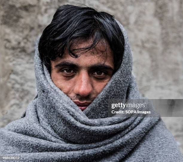 Refugee uses a UNHCR blanket to stay warm during a cold Serbian winter. The Barracks in Belgrade were abandoned buildings behind the central train...