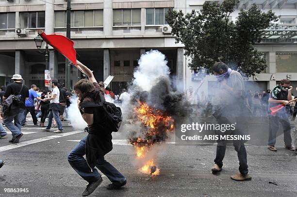 Protestors run away from a shock bomb thrown by riot police during clashes in the center of Athens on May 5, 2010. Athens police chiefs mobilized all...