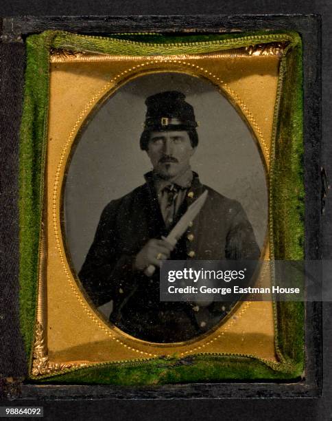 Portrait of an unidentified Civil War soldier in full uniform, holding a knife, ca.1863.