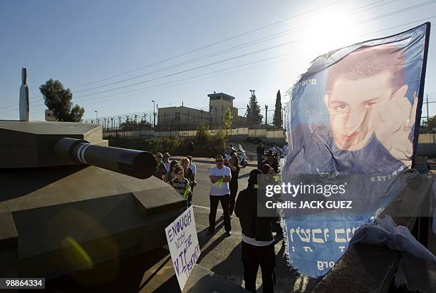 Israeli protesters stand next to a mock tank and a flag bearing a picture of captured Israeli soldier Gilad Shalit outside the Hadarim prison as they...