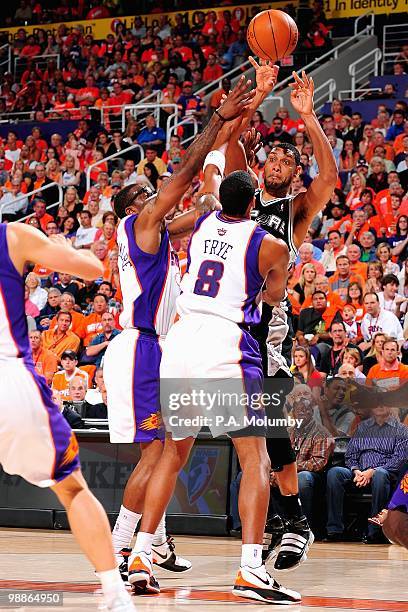 Tim Duncan of the San Antonio Spurs passes over Channing Frye and Amar'e Stoudemire of the Phoenix Suns in Game One of the Western Conference...