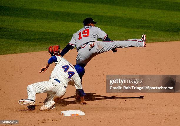 Yunel Escobar of the Atlanta Braves attempts to complete a double play as Jason Bay of the New York Mets slides into him on April 24, 2010 at Citi...