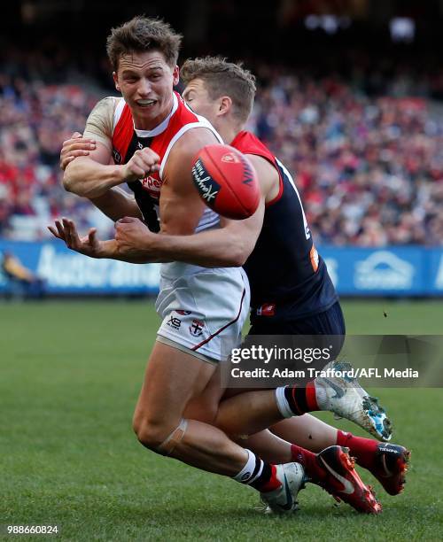 Jack Billings of the Saints handpasses the ball ahead of Jake Melksham of the Demons during the 2018 AFL round 15 match between the Melbourne Demons...