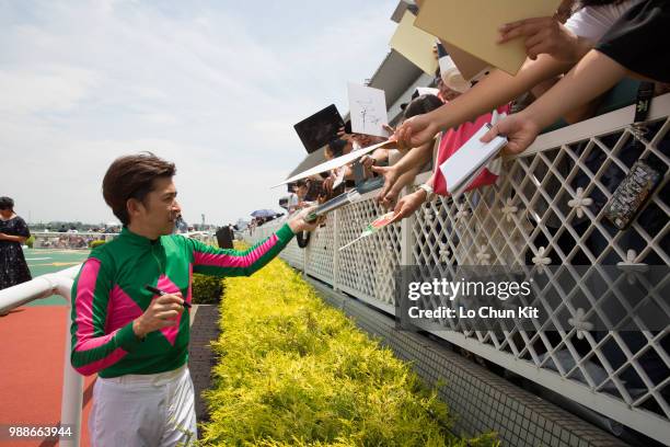 Jockey Yuichi Fukunaga gives his autograph to Japanese racing fans after Mieno Win Win winning the Race 4 at Hanshin Racecourse on June 24, 2018 in...