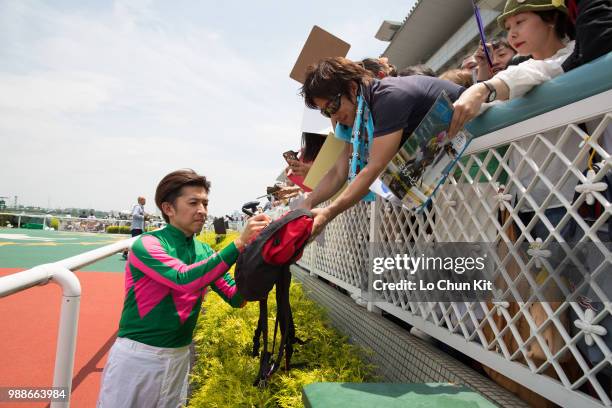 Jockey Yuichi Fukunaga gives his autograph to Japanese racing fans after Mieno Win Win winning the Race 4 at Hanshin Racecourse on June 24, 2018 in...