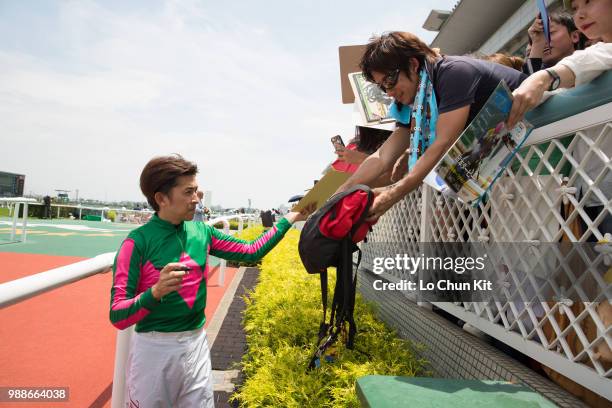 Jockey Yuichi Fukunaga gives his autograph to Japanese racing fans after Mieno Win Win winning the Race 4 at Hanshin Racecourse on June 24, 2018 in...