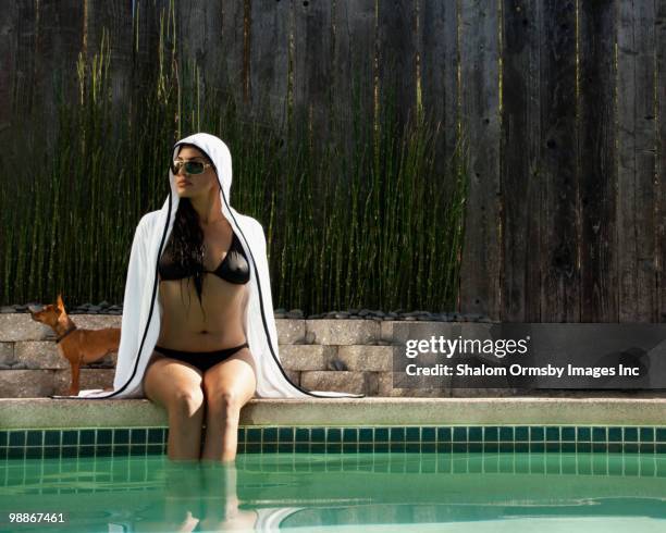 hispanic woman sitting next to swimming pool - mini robe stock pictures, royalty-free photos & images