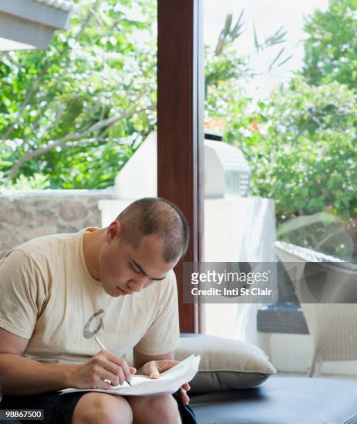 mixed race man filling out forms - inti st clair stock pictures, royalty-free photos & images
