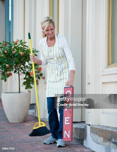 caucasian business owner sweeping sidewalk - shop broom stock pictures, royalty-free photos & images