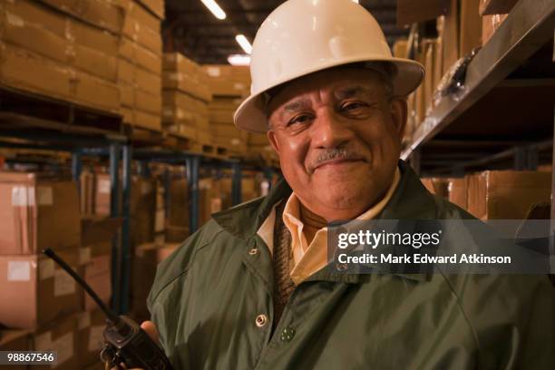 mixed race man in hard-hat in warehouse - luggage hold stock pictures, royalty-free photos & images