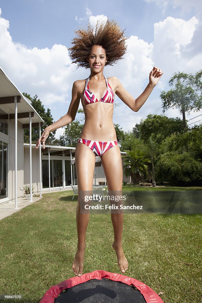 Mixed race woman jumping on mini-tram in backyard