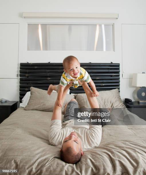 father lifting son on bed in bedroom - inti st clair stock pictures, royalty-free photos & images