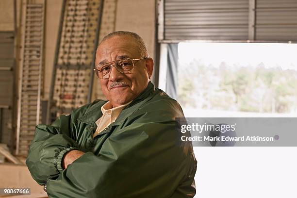 mixed race man with arms crossed in warehouse - mark atkinson stock pictures, royalty-free photos & images