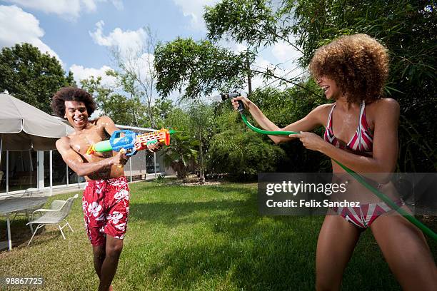 couple squirting each other with water in backyard - squirt stockfoto's en -beelden