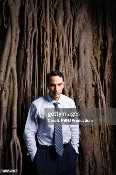 Sad Latin Businessman Standing Near Tree Roots, Foto de stock