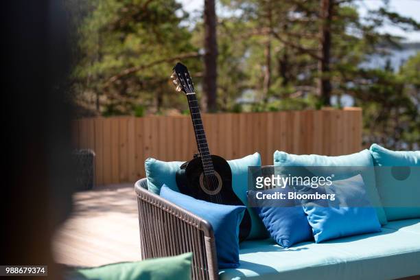 An acoustic guitar sits on an outdoor sofa on a terrace on SuperShe island near Raasepori, Finland, on Wednesday, June 27, 2018. The price of...