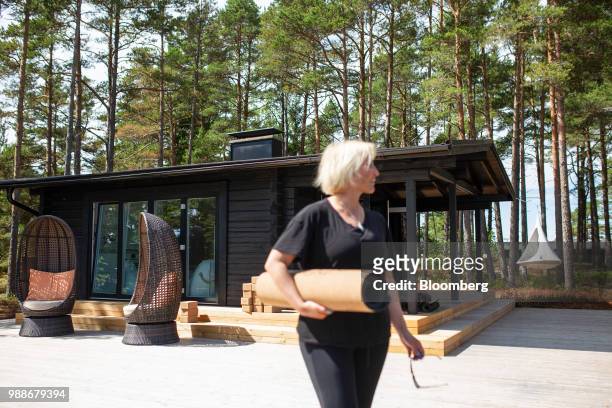 Kristina Roth, founder of the SuperShe network, carries a yoga mat in front of a guest cabin on SuperShe island near Raasepori, Finland, on...