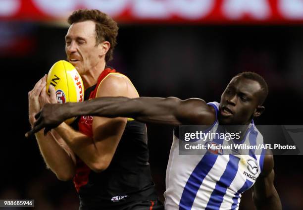 Mitch Brown of the Bombers and Majak Daw of the Kangaroos compete for the ball during the 2018 AFL round15 match between the Essendon Bombers and the...