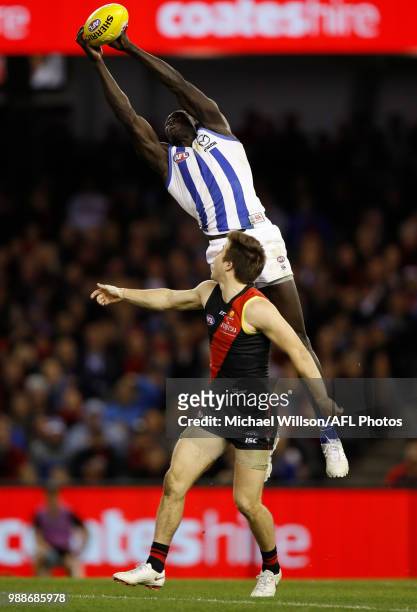 Majak Daw of the Kangaroos marks the ball over Zach Merrett of the Bombers during the 2018 AFL round15 match between the Essendon Bombers and the...