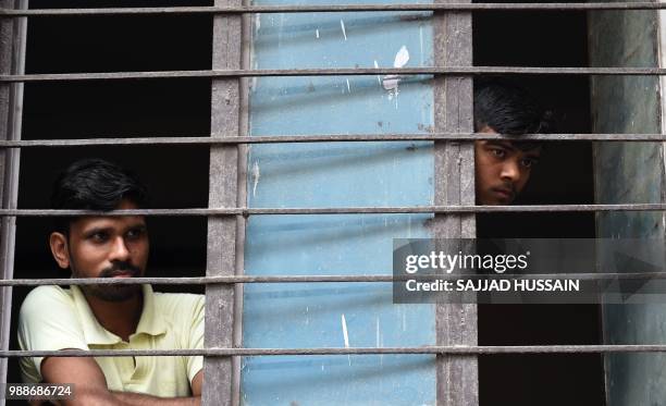 Neighbours look out from a window near the building where 11 family members were found dead inside their home in the neighbourhood of Burari in New...