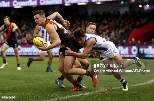Conor McKenna of the Bombers is tackled by Nathan Hrovat of the Kangaroos during the 2018 AFL round15 match between the Essendon Bombers and the...