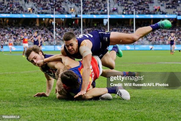 Stefan Martin of the Lions is tackled by Joel Hamling and Stephen Hill of the Dockers during the round 15 AFL match between the Fremantle Dockers and...