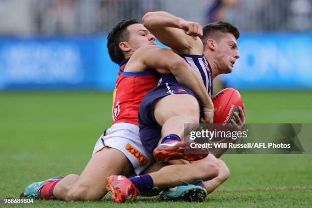 Darcy Tucker of the Dockers is tackled by Cameron Rayner of the Lions during the round 15 AFL match between the Fremantle Dockers and the Brisbane...